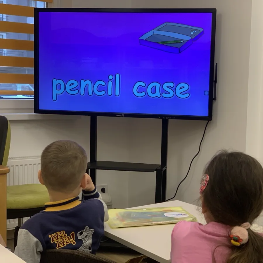 Діти дивляться на екран зі словом pencil case на занятті англійської